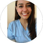 Mujer joven sonriendo con uniforme médico azul claro.